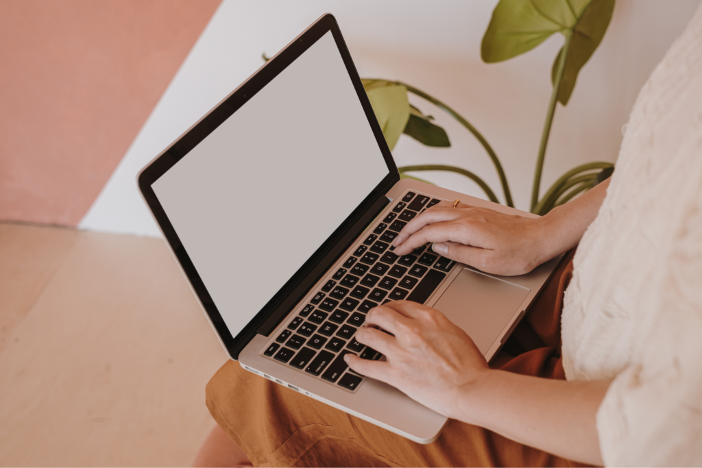 sitting with a white screen laptop on the person's lap.