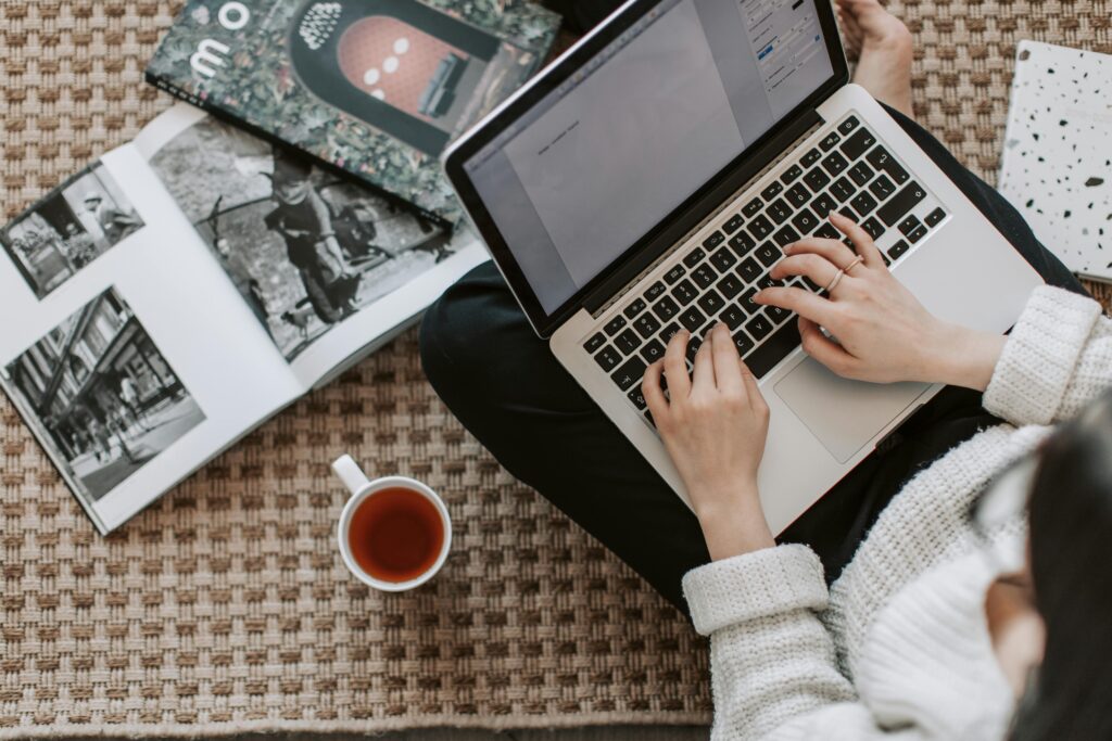 person sitting on the floor with a laptop on their lap and a coffee on the side