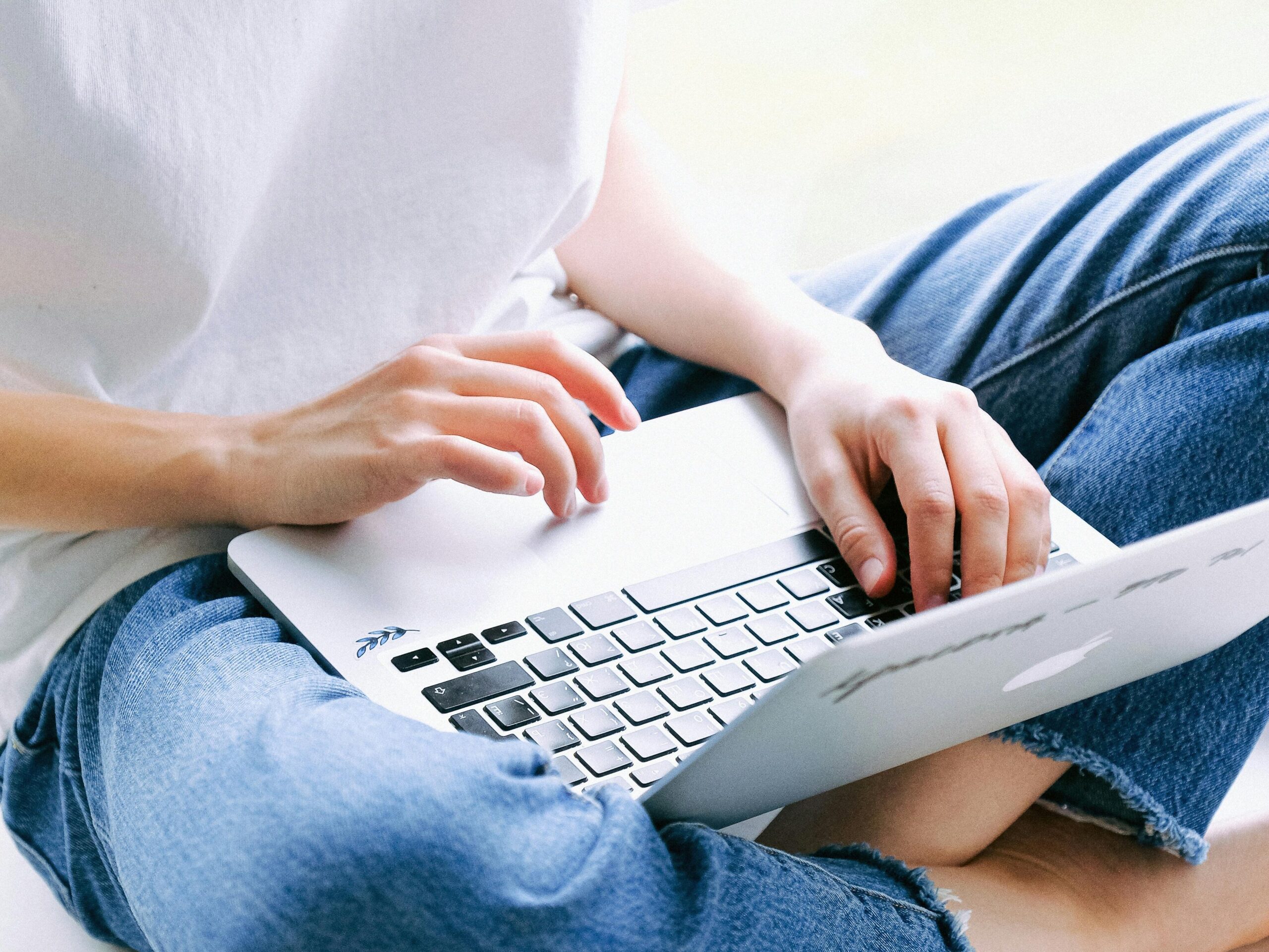 woman sitting cross legged while typing on a laptop