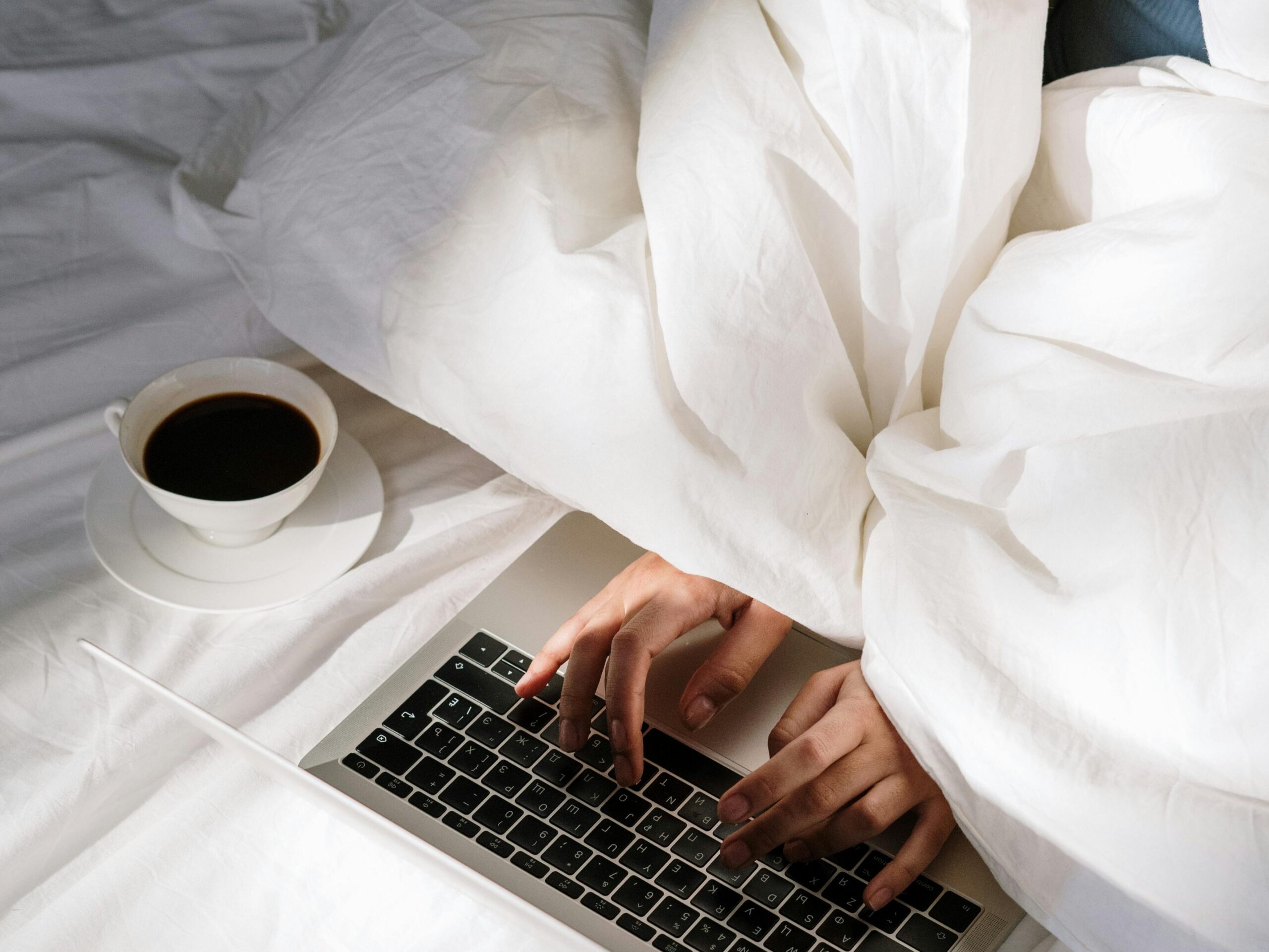 hand typing on a laptop with a coffee on the side