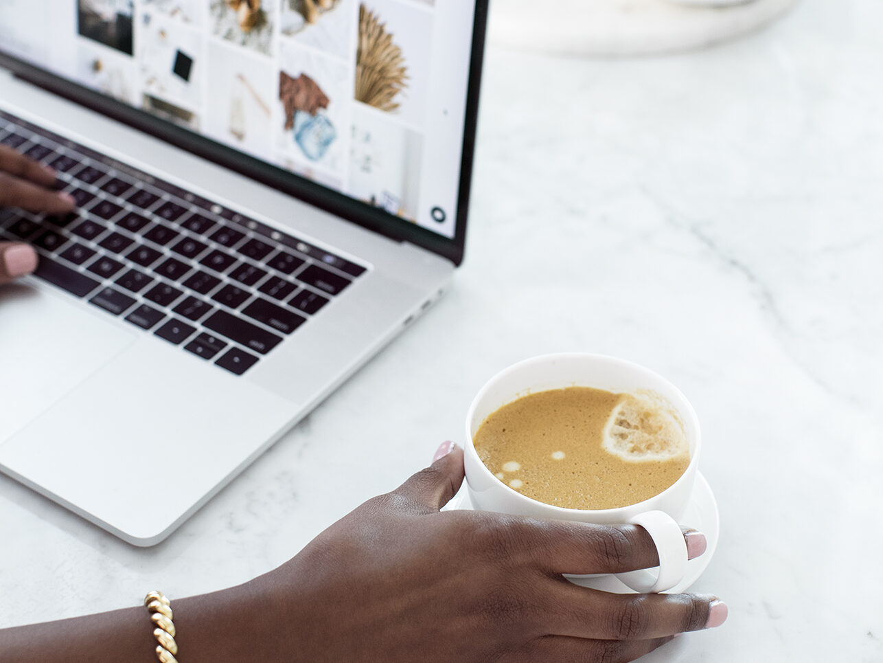 woman on a laptop and holding a coffee