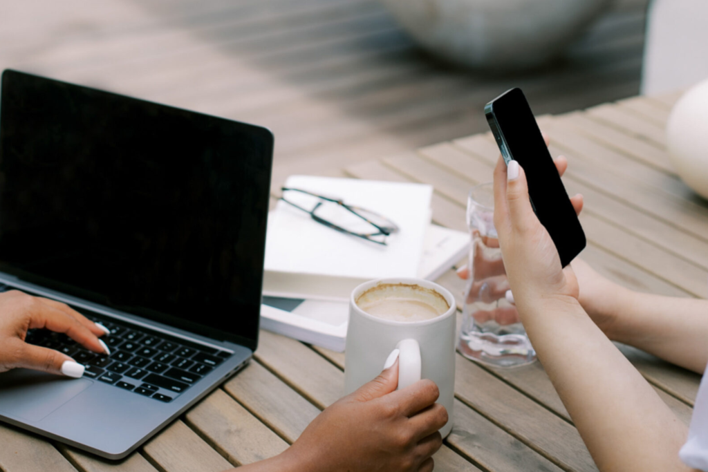 one person on a laptop while holding a coffee and another on the phone