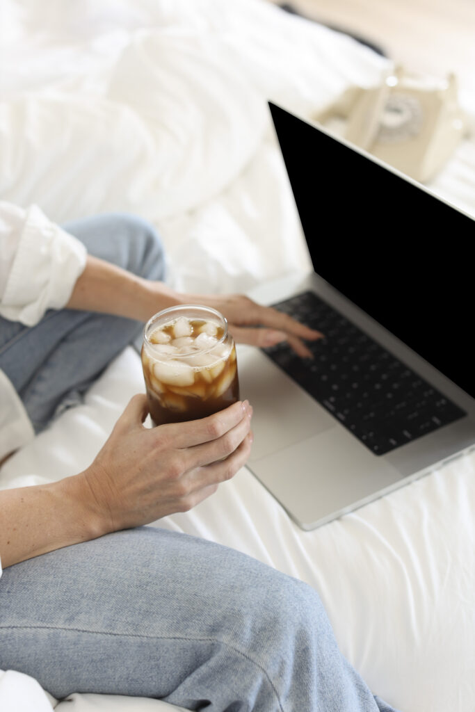 a woman holding a drink with a laptop