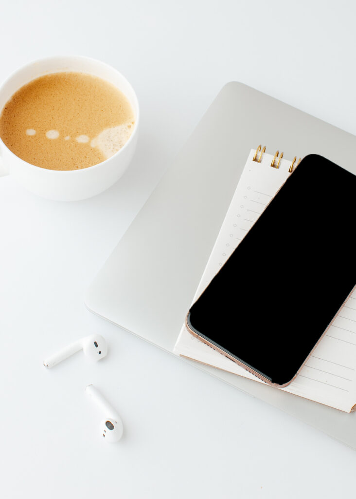 a phone on top of a notepad with a cup of coffee