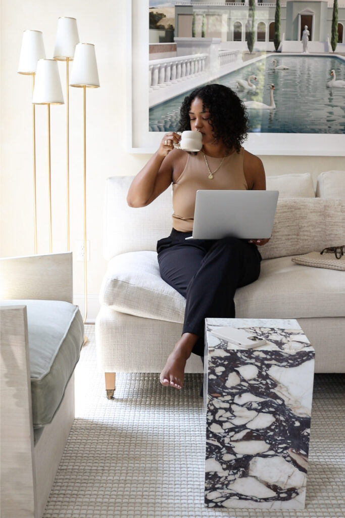 woman sipping coffee while holding a laptop 