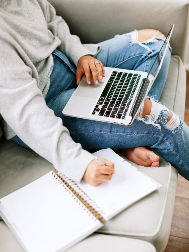 a woman with a laptop on her lap and with a pen and notebook