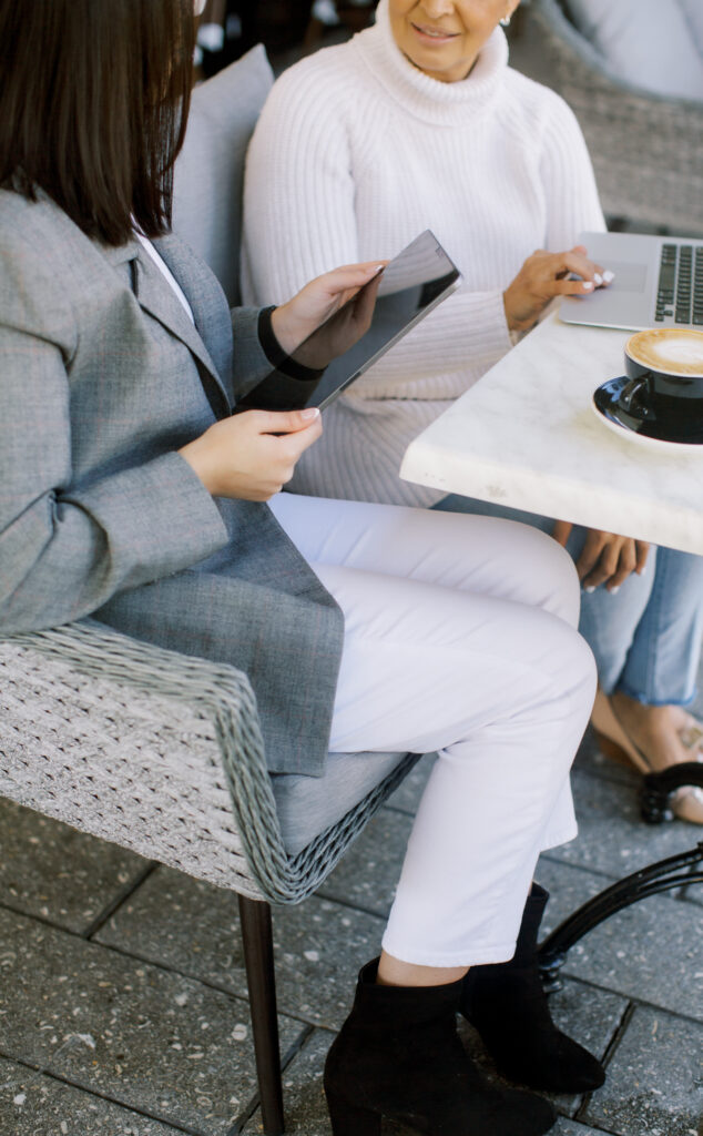 two ladies talking while holding a tablet 